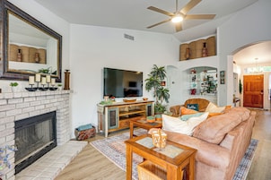 A living room with a fireplace, a television, a sofa, and a ceiling fan.
