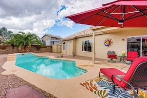 A backyard with a swimming pool, patio furniture, and a red umbrella.