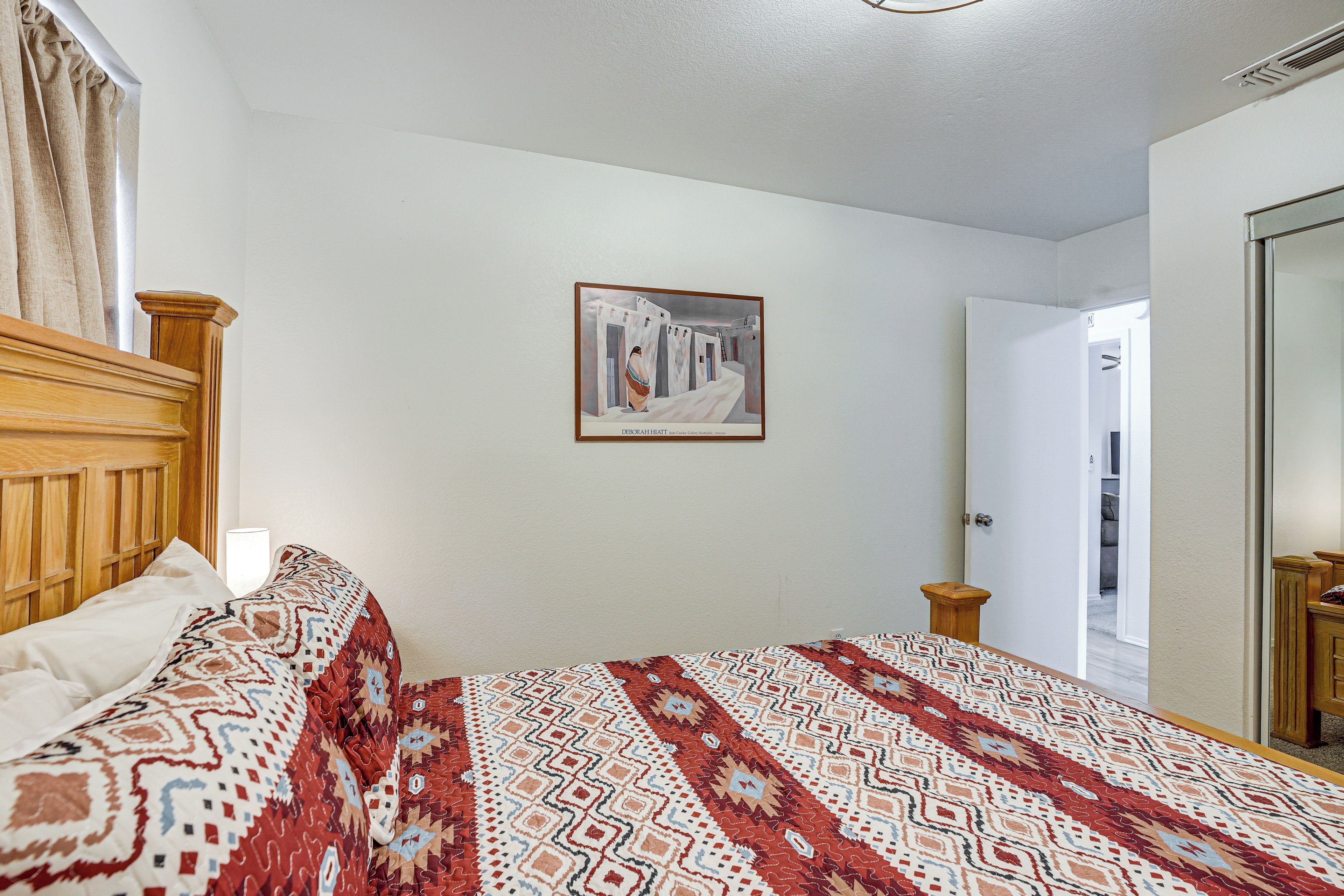 A bedroom with a bed, a nightstand, a painting on the wall, and a door.