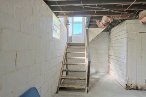 A narrow stairway leading to a door with a window, surrounded by white walls and a concrete floor. - Walkable Canton Duplex Near Fairgrounds & Dtwn! (Canton)