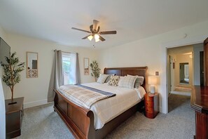 A bedroom with a bed, a nightstand, a ceiling fan, a mirror, and a plant. - Walkable Canton Duplex Near Fairgrounds & Dtwn! (Canton)