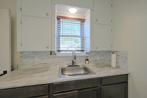 A kitchen with a built-in sink, a window with blinds, and a marble countertop. - Walkable Canton Duplex Near Fairgrounds & Dtwn! (Canton)