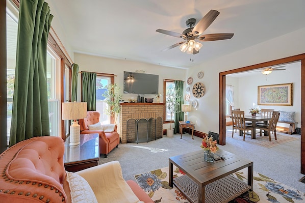 A living room with a fireplace, a television, and a dining area with chairs and a table. - Walkable Canton Duplex Near Fairgrounds & Dtwn! (Canton)