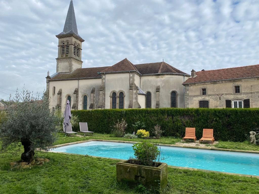 Un edificio con una torre, piscina y seto.