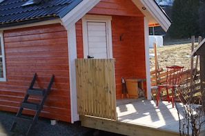 Eine Holzhütte mit Veranda, einer Tür und einer Leiter.