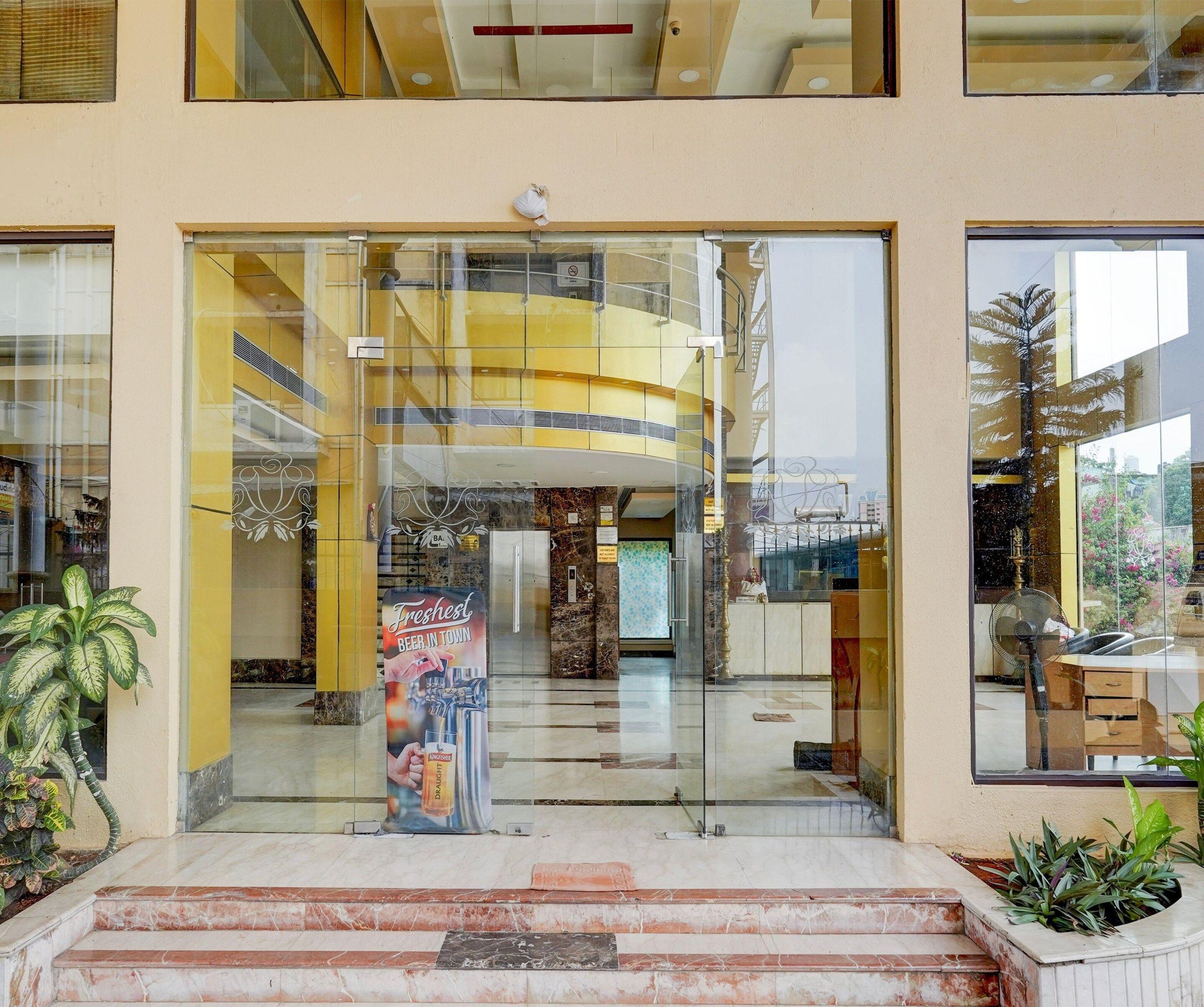 A modern building entrance with a glass door, a poster advertising beer, and a staircase leading up.