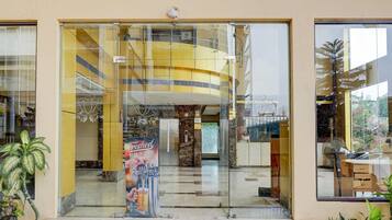 A modern building entrance with a glass door, a poster advertising beer, and a staircase leading up.