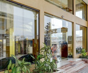 A hotel entrance with large glass doors, a staircase leading to the entrance, and potted plants. - Classic Hotel Royal Plaza (Chennai)