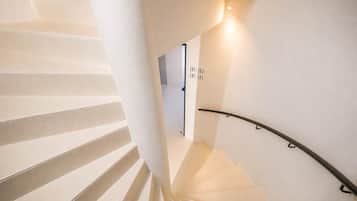 A spiral staircase with a handrail and a wall-mounted sign with room numbers.