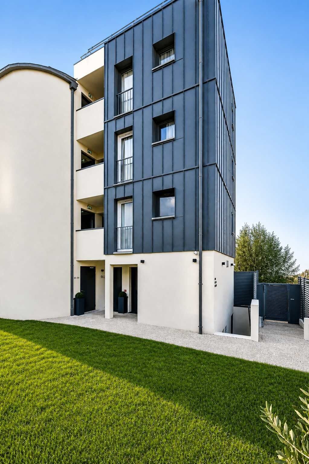Ein modernes, mehrgeschossiges Gebäude mit einer glatten Fassade, Balkonen und einem verschlossenen Eingang.