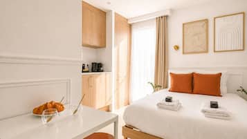 Une chambre d’hôtel comprenant un lit, une table de chevet et un coin cuisine.