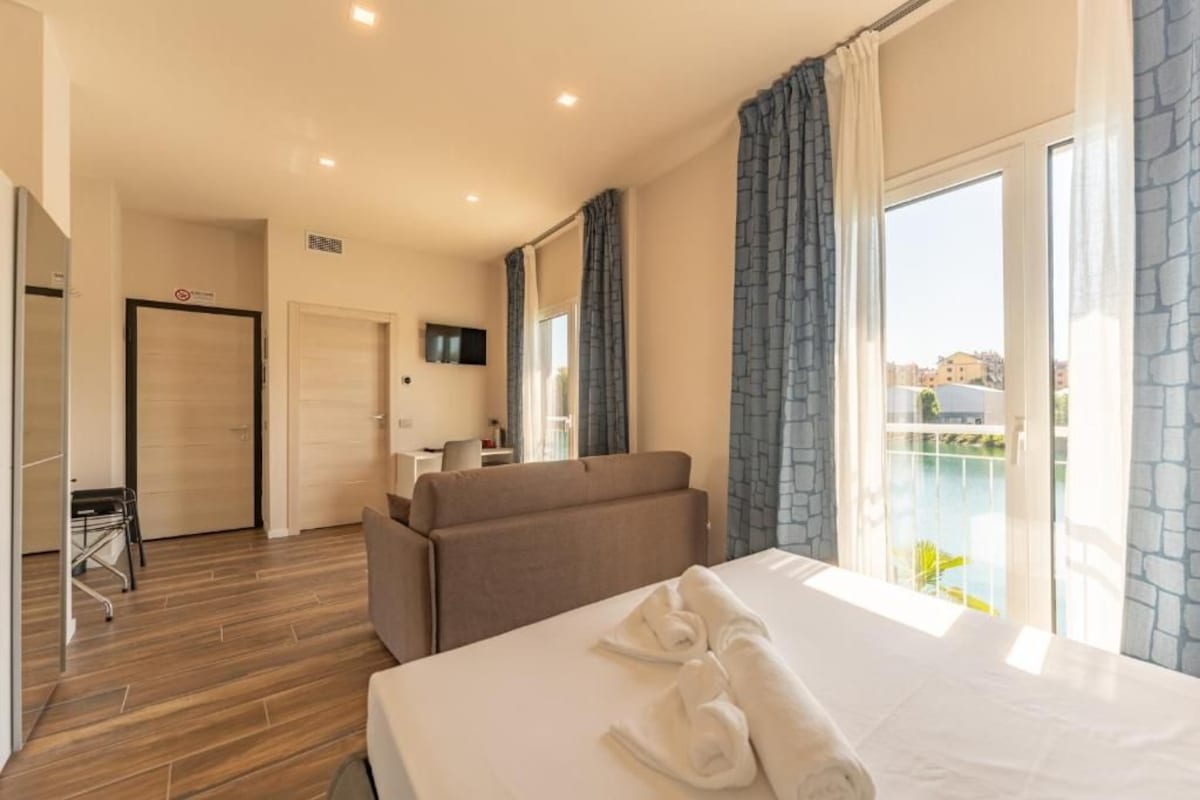 Ett hotellrum med en säng, en soffa, ett skrivbord och utsikt över omgivningarna.