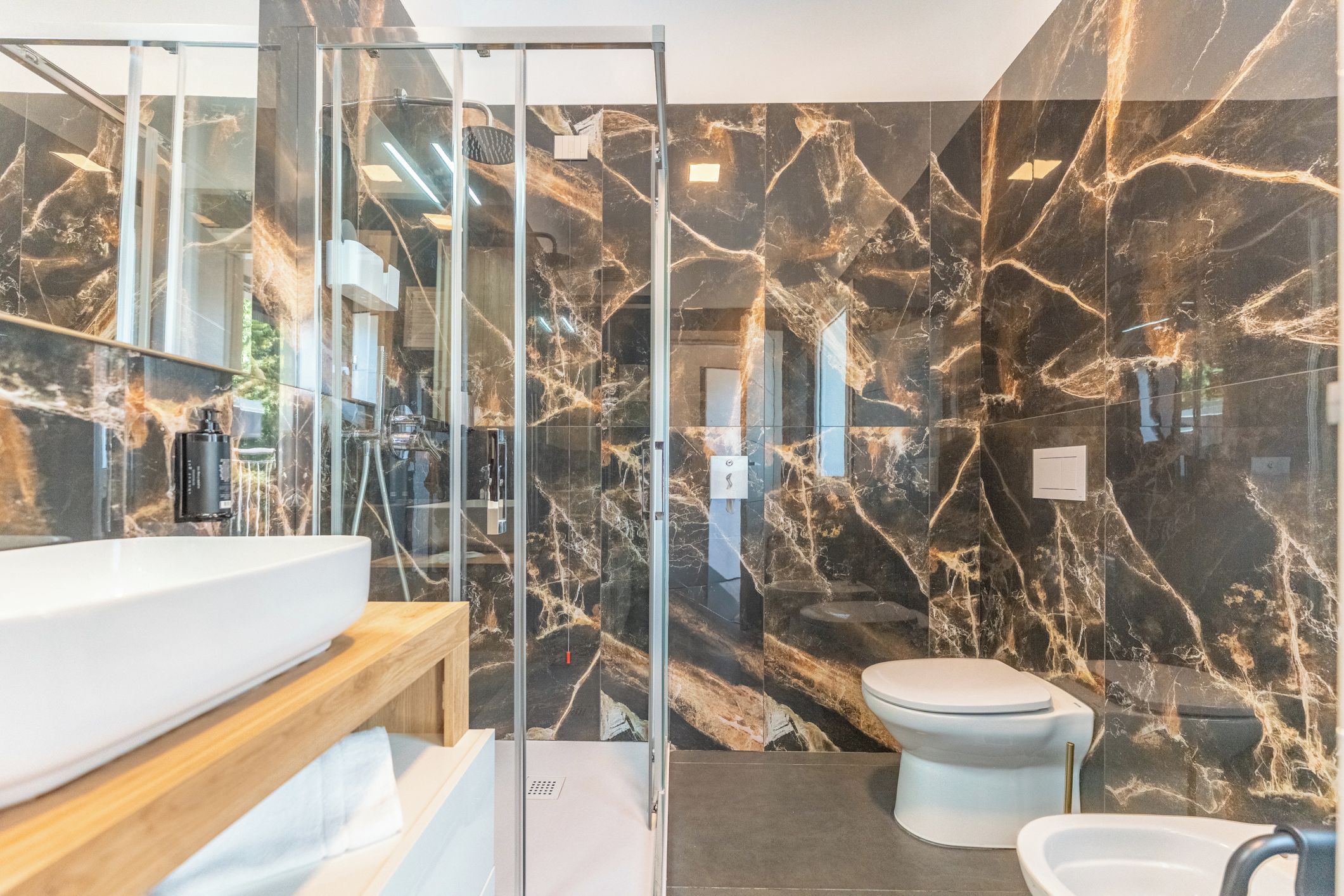 Un bagno moderno con box doccia in vetro, lavandino bianco e water.