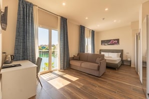 Ett modernt hotellrum med en soffa, en säng, ett skrivbord och utsikt över omgivningarna.