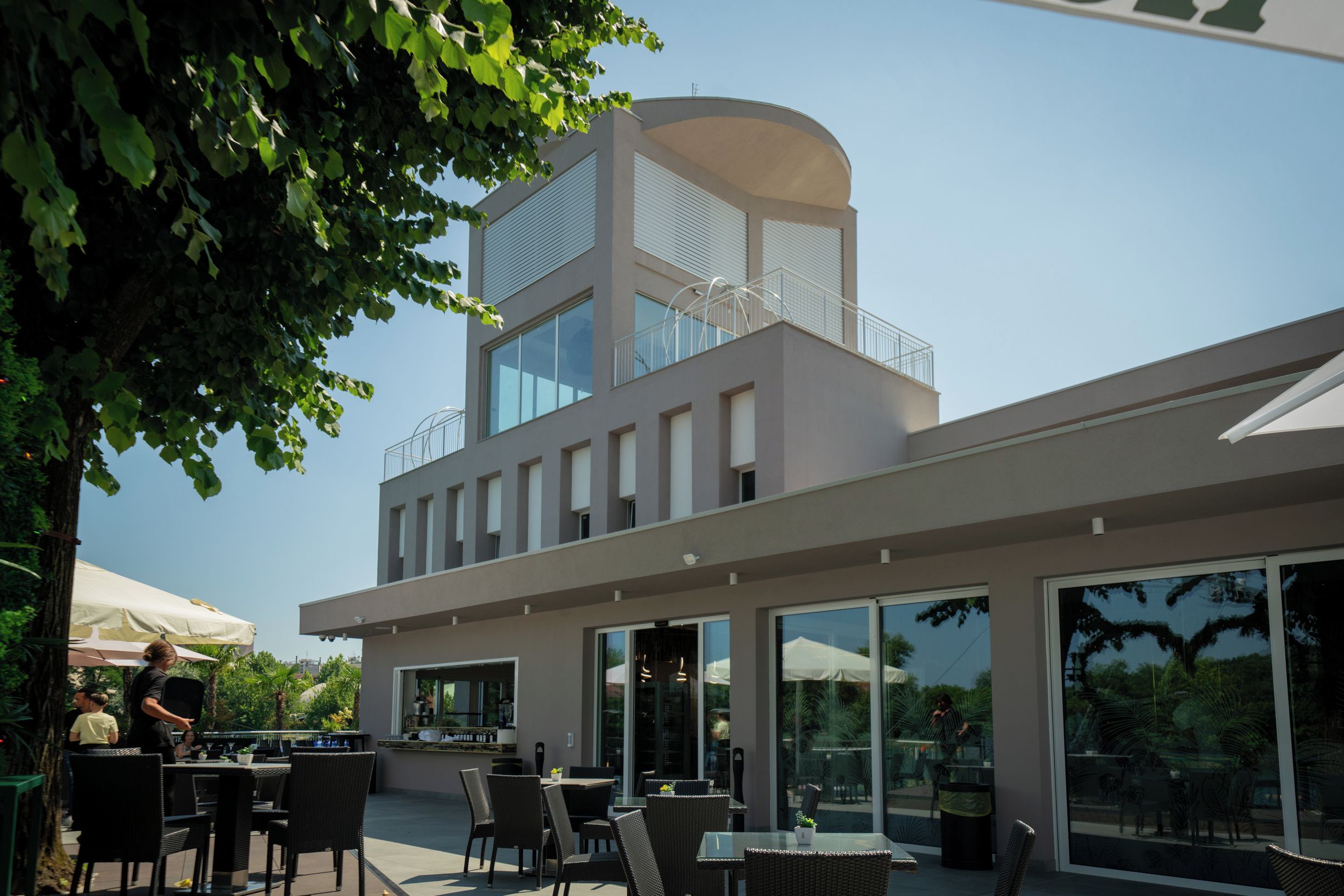Een modern gebouw met een eetgedeelte, buitenplaatsen en een glazen gevel.