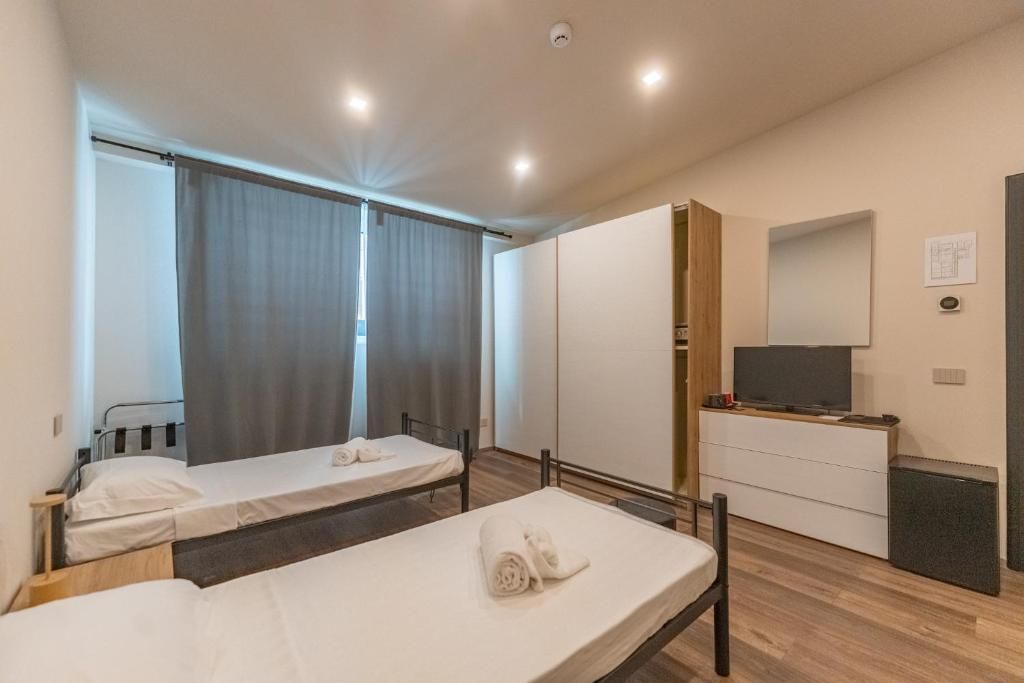 Ein Hotelzimmer mit zwei Einzelbetten, einem Fernseher, einem Schminktisch und einem Spiegel.