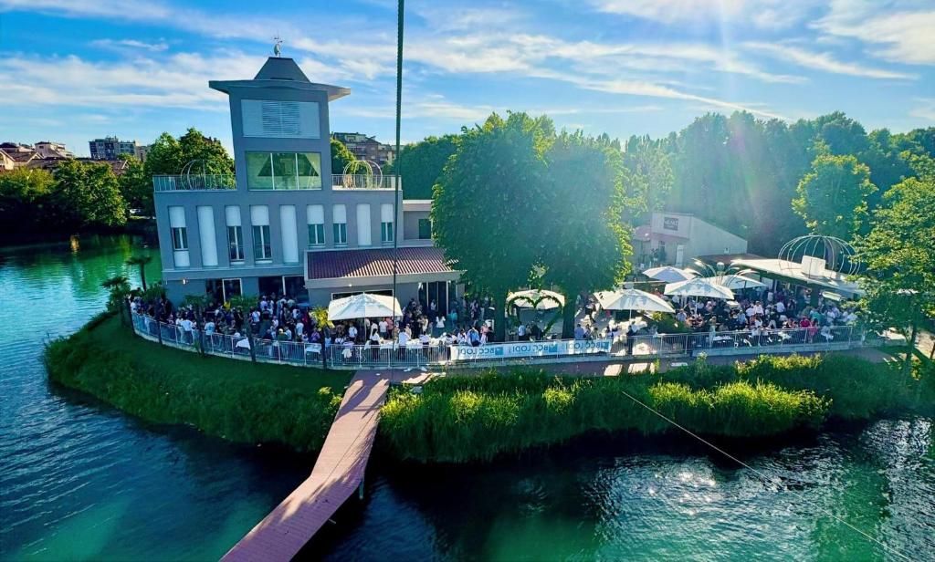 Ein Gebäude am Flussufer mit einer Aussichtsplattform, umgeben von viel Grün und einer Brücke.