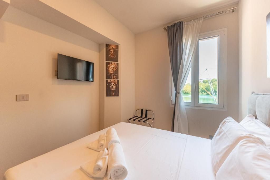 Een hotelkamer met een bed, een flatscreen televisie aan de muur, een raam met gordijnen en een handdoek op het bed.