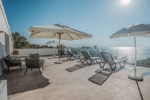 A rooftop terrace with lounge chairs and umbrellas, overlooking a coastal view. - Capovillas - Villa Vittoria with pool and ocean view (Coccorino)