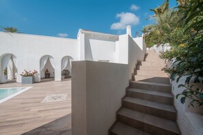 Ein Poolbereich mit Stufen, die zu einer überdachten Terrasse führen.