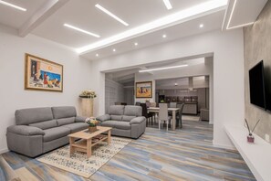 Een moderne woonkamer met een bank, salontafel en een eethoek op de achtergrond.
