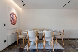 A dining area with a round table, six chairs, and a large abstract painting on the wall. - 3 Bedroom Apartment at Glyfada’s Centre (Glyfada)
