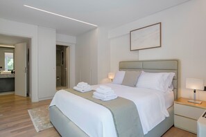 A modern bedroom with a bed, bedside tables, a nightstand, and a bathroom visible through an open door. - 3 Bedroom Apartment at Glyfada’s Centre (Glyfada)