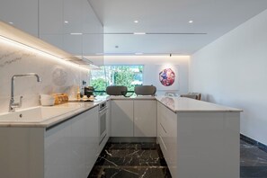 A modern kitchen with a marble countertop, a built-in oven, and a window providing a view of greenery. - 3 Bedroom Apartment at Glyfada’s Centre (Glyfada)