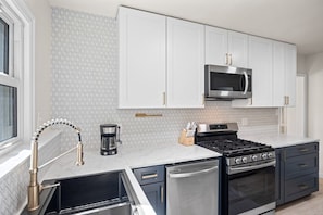 A modern kitchen with white cabinets, a stainless steel microwave, a gas stove, and a dishwasher. - Bright 3BR Home Near MetraPark & Downtown Billings (Billings)