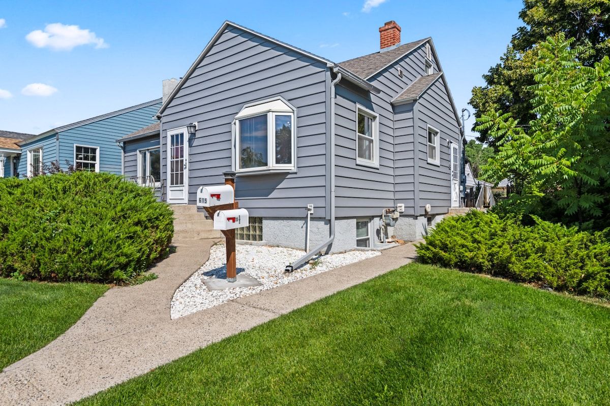A residential house with a front porch, a mailbox, and a well-maintained lawn.