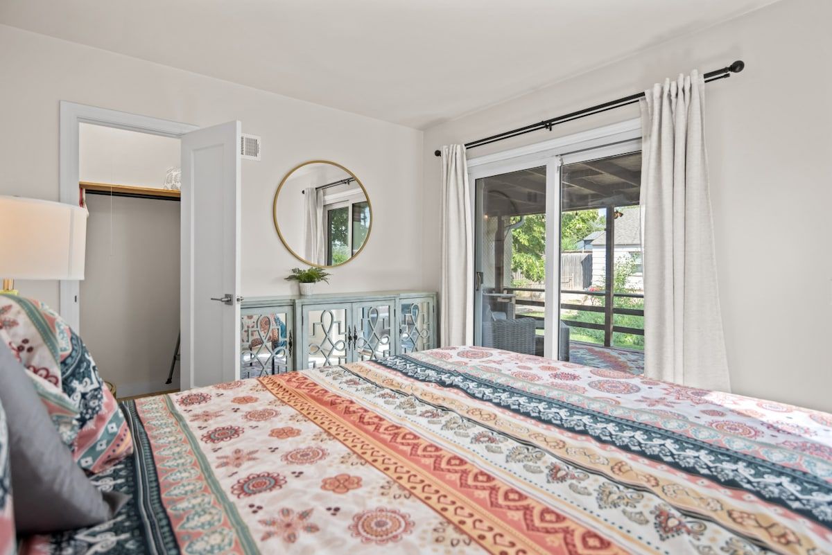 A bedroom with a bed, a mirror, a wardrobe, and a window with curtains.