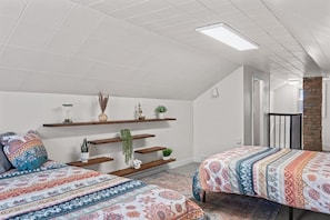 A bedroom with two beds, a skylight, a brick wall, and a staircase. - Bright 3BR Home Near MetraPark & Downtown Billings (Billings)