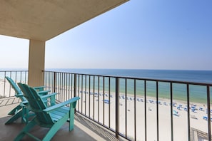 A balcony with a view of a beach, featuring a railing and a pair of chairs. - Phoenix Ii 2104 1 Bedroom Condo (Orange Beach)