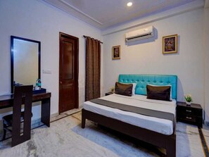 A bedroom with a bed, a desk, a chair, a door, and an air conditioning unit. - Classic Sangam Vihar (Ghaziabad)