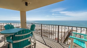 Ein Balkon mit Blick auf den Strand, einem Tisch und Stühlen.