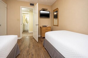A hotel room with two beds, a TV, a mirror, and a wooden dresser. - Phoenix Ii 2112 2 Bedroom Condo (Orange Beach)