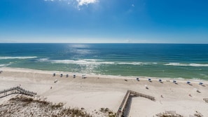 A beach with a wooden walkway leading to the water, a row of umbrellas, and a clear view of the ocean. - Phoenix Ii 2112 2 Bedroom Condo (Orange Beach)