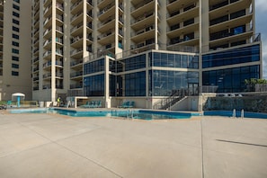 A modern hotel with a pool area, multiple balconies, and a glass facade. - Phoenix Ii 2126 1 Bedroom Condo (Orange Beach)