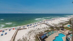 A beach resort with a swimming pool, beach umbrellas, and a wooden boardwalk. - Phoenix Ii 2092 2 Bedroom Condo (Orange Beach)