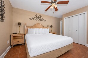 A bedroom with a bed, nightstands, a ceiling fan, a wall decoration, and a wardrobe. - Phoenix Ii 2117 2 Bedroom Condo (Orange Beach)