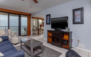 Ein Wohnzimmer mit Flachbildfernseher, einer Couch, einem Couchtisch und einem Balkon mit Blick.