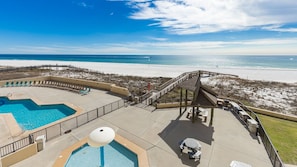 A pool area with a view of the beach, a wooden deck, and a lifeguard stand. - Phoenix Ii 2022 2 Bedroom Condo (Orange Beach)