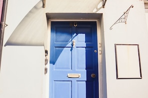 Une porte bleue avec une fente pour le courrier et une petite fenêtre sur le côté droit.