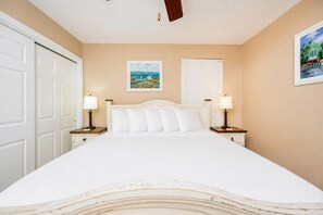 A bedroom with a large bed, two bedside tables with lamps, a door, and two framed pictures on the walls. - Phoenix Ii 2048 3 Bedroom Condo (Orange Beach)