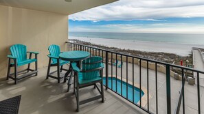 A balcony with a view of the beach, a pool, and outdoor seating. - Phoenix Ii 2024 1 Bedroom Condo (Orange Beach)