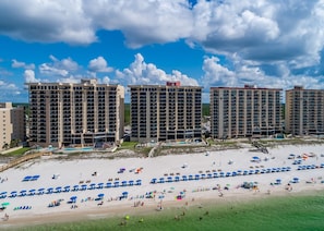 A beachfront hotel with multiple high-rise buildings, a sandy beach with umbrellas, and a pool area. - Phoenix Ii 2024 1 Bedroom Condo (Orange Beach)