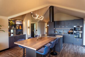 Una cocina moderna con una isla central, taburetes de bar y electrodomésticos integrados.