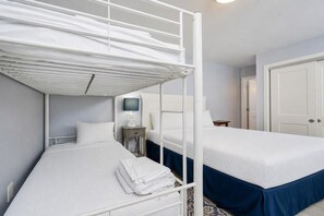 A room with bunk beds, a bedside table with a lamp, and a door. - Phoenix Ii 2097 2 Bedroom Condo (Orange Beach)