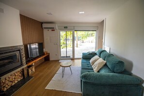 A living room with a flat-screen TV, a sofa, a small table, and a fireplace.