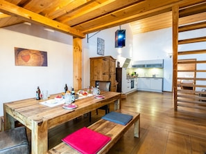 A wooden dining table with benches, a kitchen area, and a loft space with a wooden staircase. - Mayrhof - Mountain View (Eggstatt)
